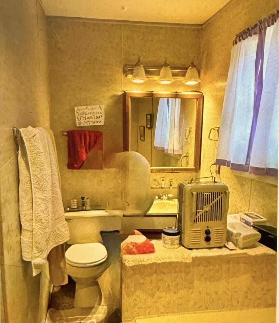 Older bathroom before renovation with vanity, mirror, toilet, and dated finishes
